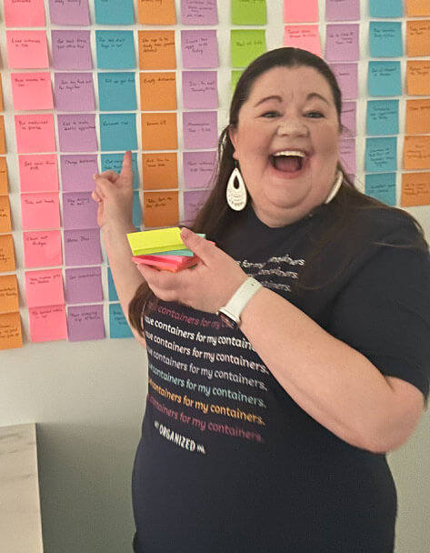 Laura excitedly pointing to her sticky note wall