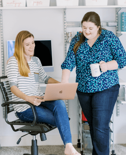 Laura pointing to something on a laptop screen in Tasha'a lap