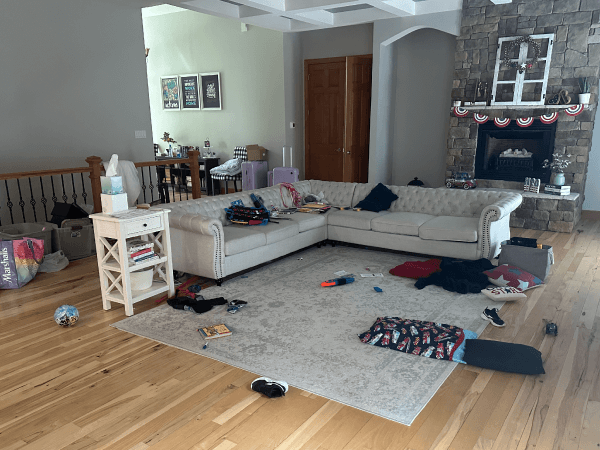 A living room with random items strewn about on the floor and sofa