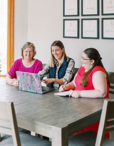 A group of ladies looking at a laptop together at a kitchen table