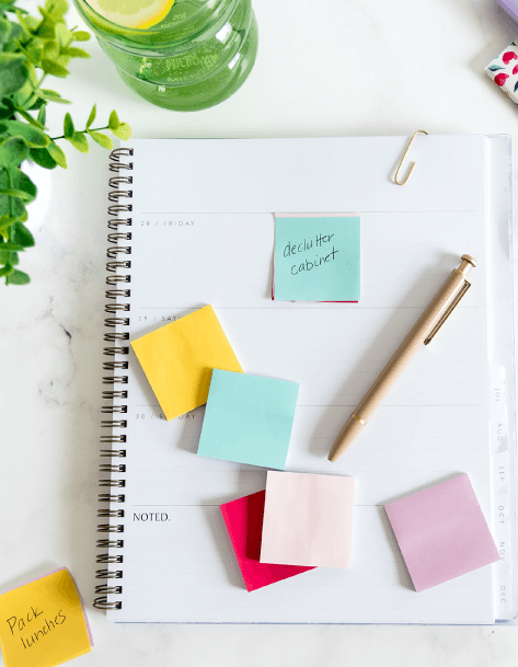 A sticky note placed in a planer that says 'declutter cabinet"