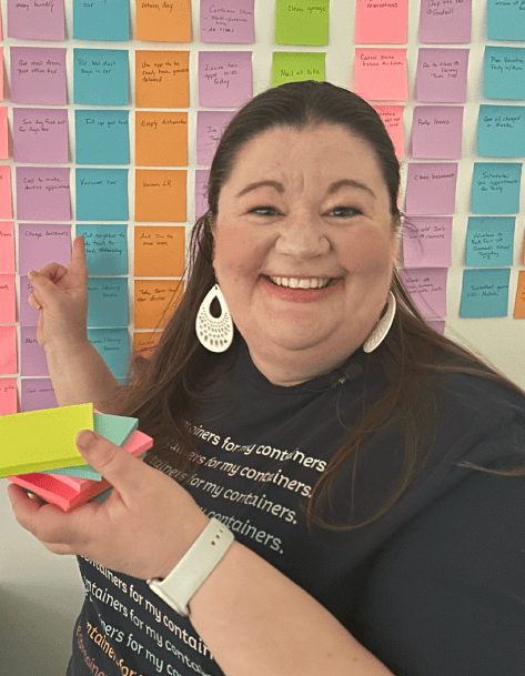Laura smiling in front of her sticky note wall