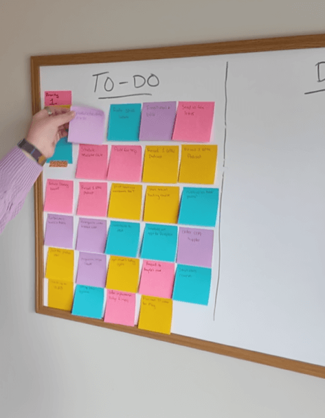 Laura putting a "to-do sticky note on her board