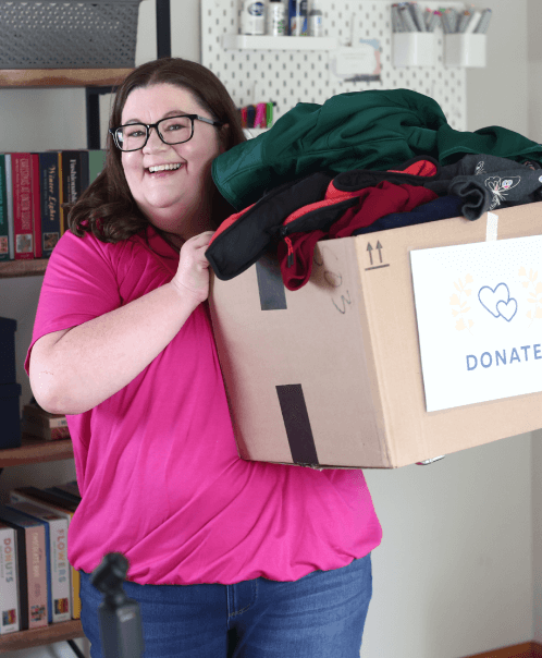 Laura holding a box of clothes with a "Donate" sign on them